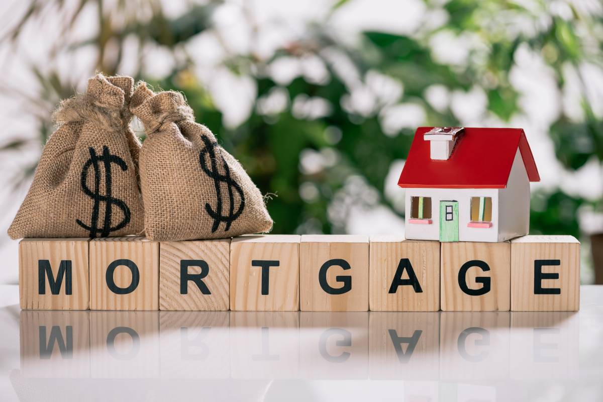 selective focus of moneybags with dollar signs and house model on wooden cubes with letters,