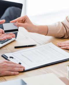 cropped view of patient at table with insurance claim form giving credit card to doctor cropped view of patient at table with insurance claim form giving credit card to doctor